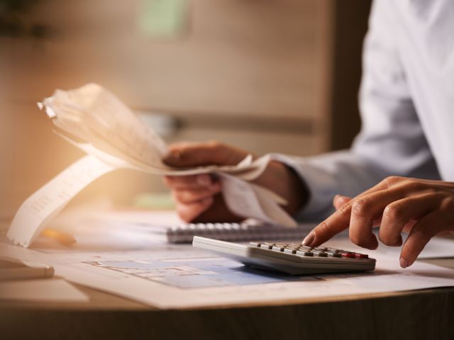 Close-up of business accountant using calculator while working i